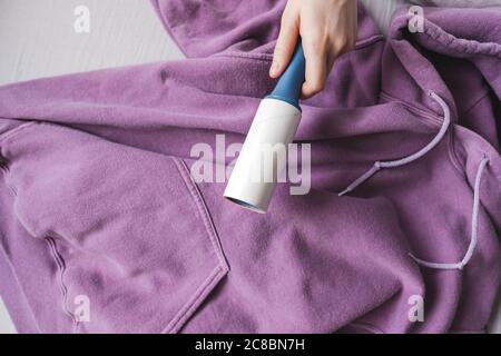 Hands holding blue sticky roller for cleaning clothes. Stock Photo