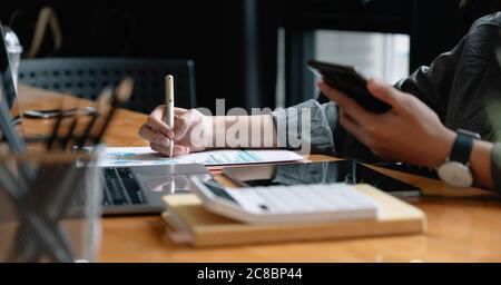 Businessman pen pointing turnover with graph chart report and use laptop computer for analysis data Stock Photo