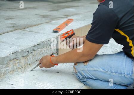 Man using hammer and chisel to dig up concrete floor during house renovations Stock Photo