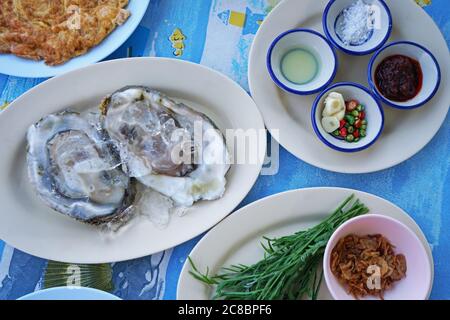 Close up fresh oyster served with Thai style dipping sauce, garlic and vegetables Stock Photo