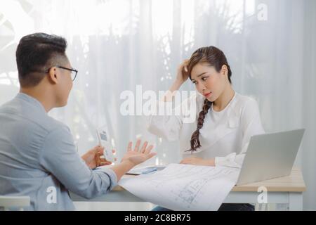 Two colleagues discussing data working and tablet, laptop with on on architectural project at construction site at desk in office Stock Photo