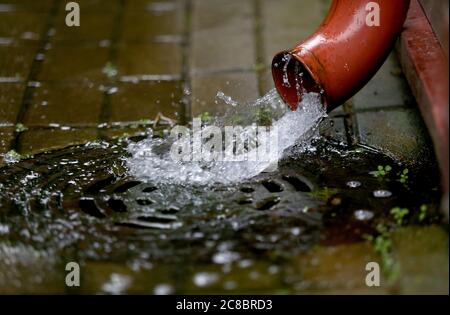 Rain water is pouring from the green draining gutter on the pavement, selective focus, Nida, Lithuania Stock Photo