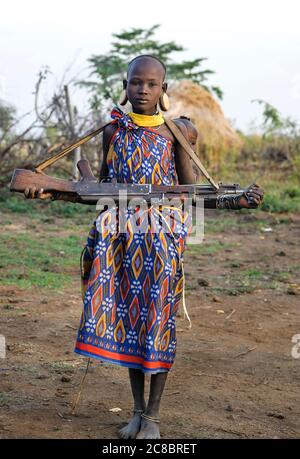 Ethiopia - Africa,  January 03. 2014: Girl of Mursi Tribe with Kid and Machinegun, Mago National Park, Ethiopia, Africa Stock Photo