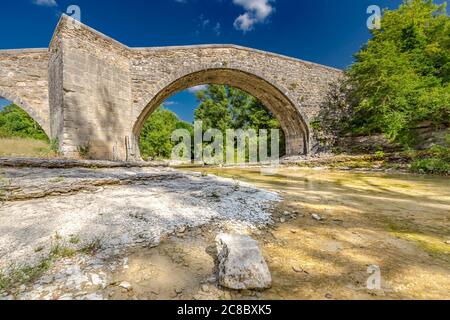 Romanesque Bridge of Mane. Old stone bridge in summer with green trees and blue sky. Idyllic historic architecture Stock Photo