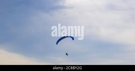 a man on a paraglider on the background of a cloudy blue sky