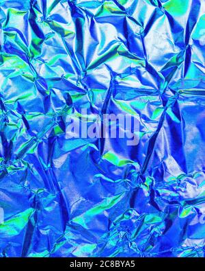 Texture of crumpled aluminum kitchen foil with reflected violet and green light. Stock Photo