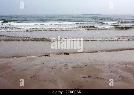 The North Sea and Inner Farne Island from Bamburgh Sands, Northumberland, England, UK on a dull, cloudy day Stock Photo