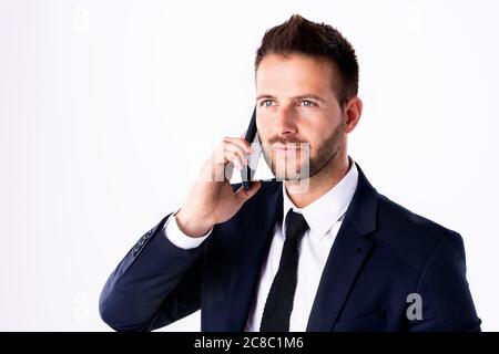Close-up shot of handsome man wearing suit while standing at isolated white background and using his mobile phone. Copy space. Stock Photo