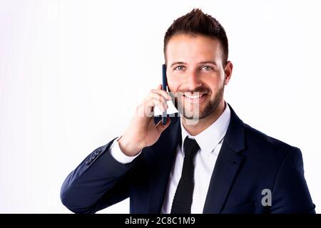 Close-up shot of handsome man wearing suit while standing at isolated white background and using his mobile phone. Copy space. Stock Photo