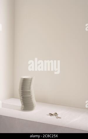 Spoons next to stack of plates on table Stock Photo