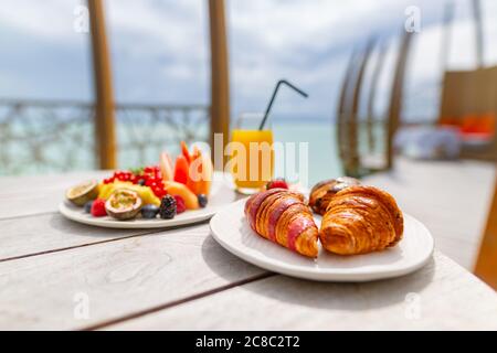 Delicious organic fruits, eggs, juice and coffee served for breakfast at tropical ocean edge in a luxury resort Stock Photo