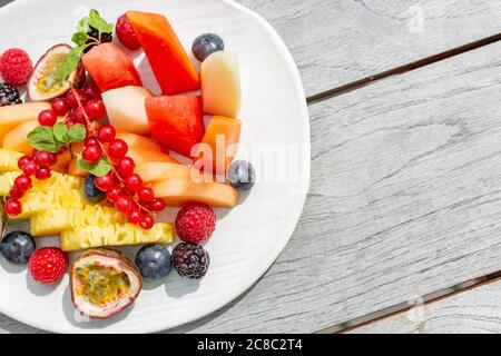 Tropical fruit salad with mango and pitaya in bowl on wooden table. Healthy fruit salad. Dietary breakfast. Stock Photo
