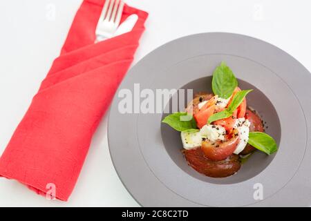 Luxury salad isolated on white with cutlery and red napkin. Gourmet tomato and mozzarella salad Stock Photo