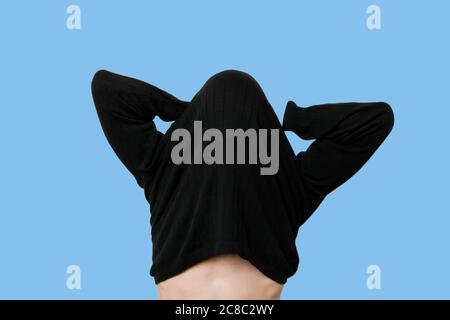 Young man having trouble putting on sweater Stock Photo