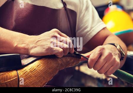 Cobbler craftsman fixing leather boot using tools Stock Photo