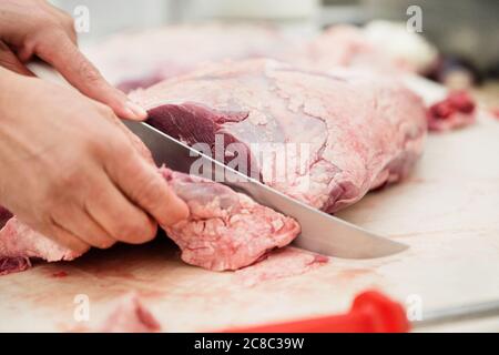 Close up of butcher caving piece of meat in butchers Stock Photo