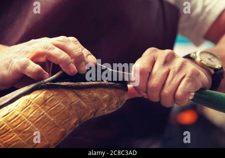 Cobbler craftsman fixing leather boot using tools Stock Photo