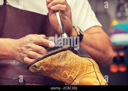 Cobbler craftsman fixing leather boot using tools Stock Photo
