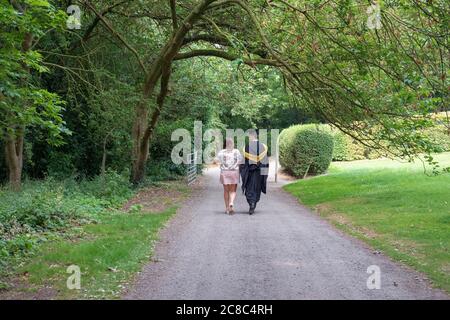 Young couple seen walking in the grounds of a famous UK university. The man is seen wearing his graduation gown and mortar board/ Stock Photo