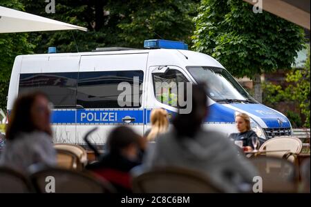 Berlin, Germany. 23rd July, 2020. A police emergency vehicle drives past a restaurant on Alexanderplatz. According to the district mayor of Mitte, the Corona rules are being ignored more and more frequently in bars, pubs and restaurants. Credit: Britta Pedersen/dpa-Zentralbild/dpa/Alamy Live News Stock Photo