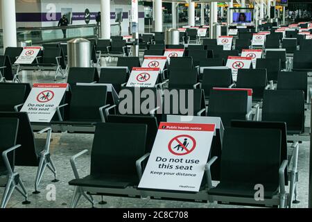 HEATHROW LONDON UK. 23 July, 2020. Public health notice social distancing signs are placed on seats  inside Heathrow airport terminal  to prevent passengers from sitting too close together during the coronavirus pandemic to  stop the spread of Covid-19 infections. Credit: amer ghazzal/Alamy Live News Stock Photo