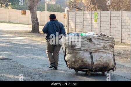 Alberton, South Africa - unidentified black female collects objects to recycle for resale from household refuse bins in a residential neighbourhood Stock Photo
