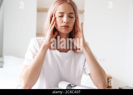 Image of tire attractive woman with headache doing homework while sitting at table in home Stock Photo