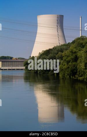 The cooling tower of a nuclear power plant is reflected in a river. In front of it is a hydropower plant. Everything in close-up. Stock Photo