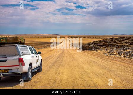 Namib Desert, Namibia - March 29, 2019 : Typical 4x4 rental car in Namibia equipped with camping gear and a roof tent driving on a dirt road in Namib Stock Photo