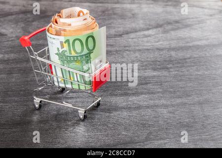 Shopping Cart Full of Cash. Shopping consept, euro money in cart. Shopping cart with euro banknotes on grey desk. Copy space for text. Stock Photo