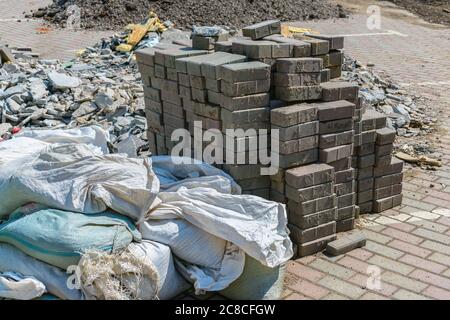Construction waste in bags, broken stone and a pile of bricks during industrial work Stock Photo