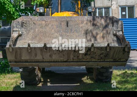 Excavator bucket on the lawn near the construction site close up Stock Photo