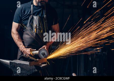 Worker Using Angle Grinder in Factory and throwing sparks Stock Photo