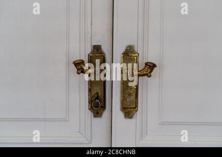 Close-Up Of A White Closed double Door. Gold-plated Door handles on the door Stock Photo