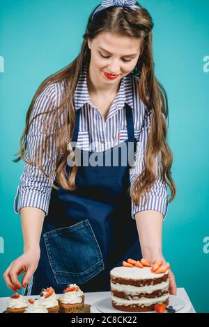 Caucasian pastry female in stripped blouse decorating cake with strawberry Stock Photo