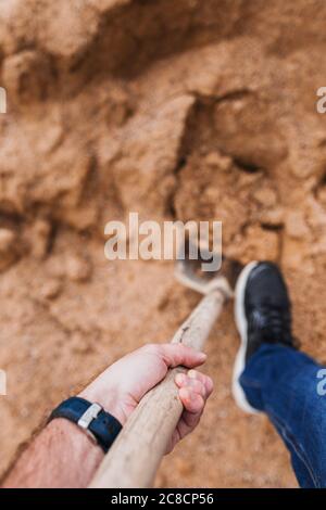 Man digs a hole in the sand in search of treasure - shovel in hand - first person view Stock Photo