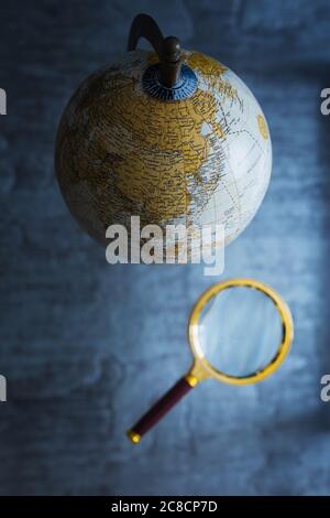 Geographic globe with a map of the planet earth for navigation and travel - secrets of the planet - geographer golden magnifier Stock Photo