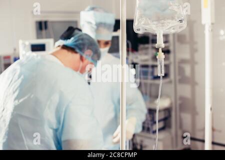 Doctor's hand and infusion drip in hospital on blurred background Stock Photo