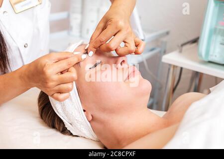 Beauty salon. The cosmetologist gives a facial massage to the client. Close up of face. Concept of professional cosmetology. Stock Photo