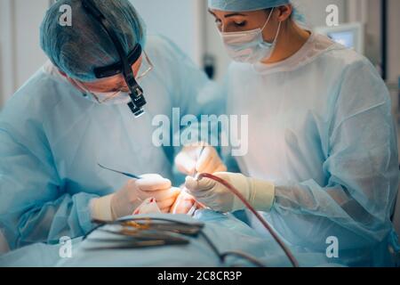 Team of surgeon in uniform perform operation on a patient at plastic surgery clinic Stock Photo
