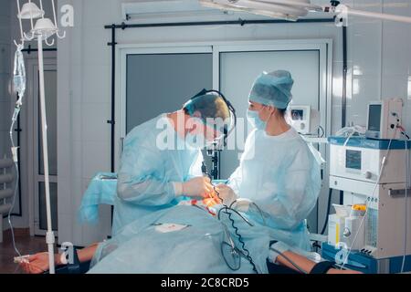 Team of surgeon in uniform perform operation on a patient at plastic surgery clinic Stock Photo