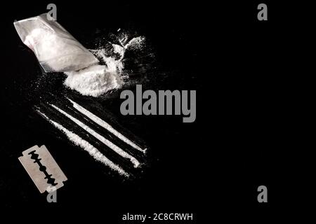 Drug addiction and substance abuse concept theme with lines of cocaine, a small bag with white powder and a blade used to cut each line of narcotics o Stock Photo