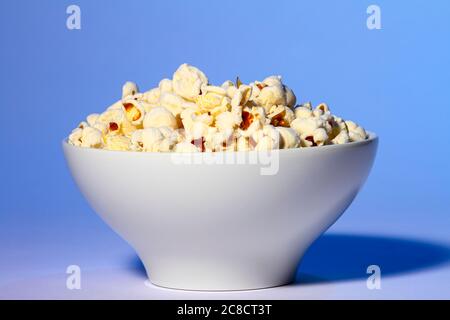 Bowl of fresh popcorn isolated on a blue background Stock Photo