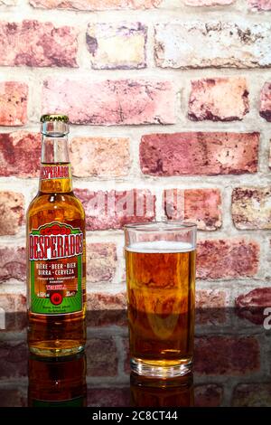 Bottle and glass of desperados tequila flavoured lager on a glass table top Stock Photo