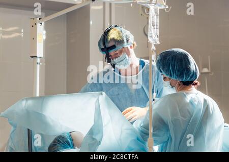 surgery, healthcare, medicine and people concept - nurse assisting surgeon and helping with gloves in operating room at hospital with diagram and virt Stock Photo