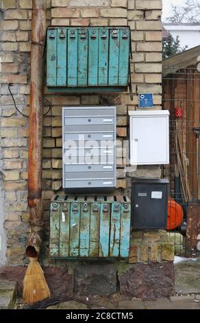 Old and new rusty mailboxes mounted on the wall of a yellow brick house of old city Stock Photo