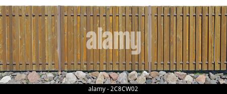Long old solid aged brown  wooden rural fence from vertical planks. Base made from granite stones. Isolated on white  panoramic collage Stock Photo