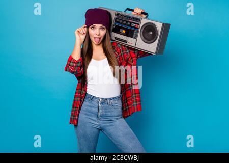 Photo of good mood pretty lady spring day weather rejoicing walking street hold tape recorder shoulder sticking tongue wear casual hat plaid shirt Stock Photo