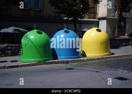 Three colored bins for sorting waste located in the city on the street.Trash Containers for Garbage Separation -- three colors for plastic, metal and Stock Photo