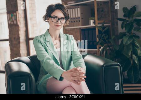 Portrait of coo,independent girl economist financier sit armchair wait for business start up development appointment wear blazer jacket trousers in Stock Photo